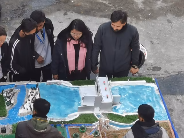 Visitors examining a scale model of a building complex with a swimming pool