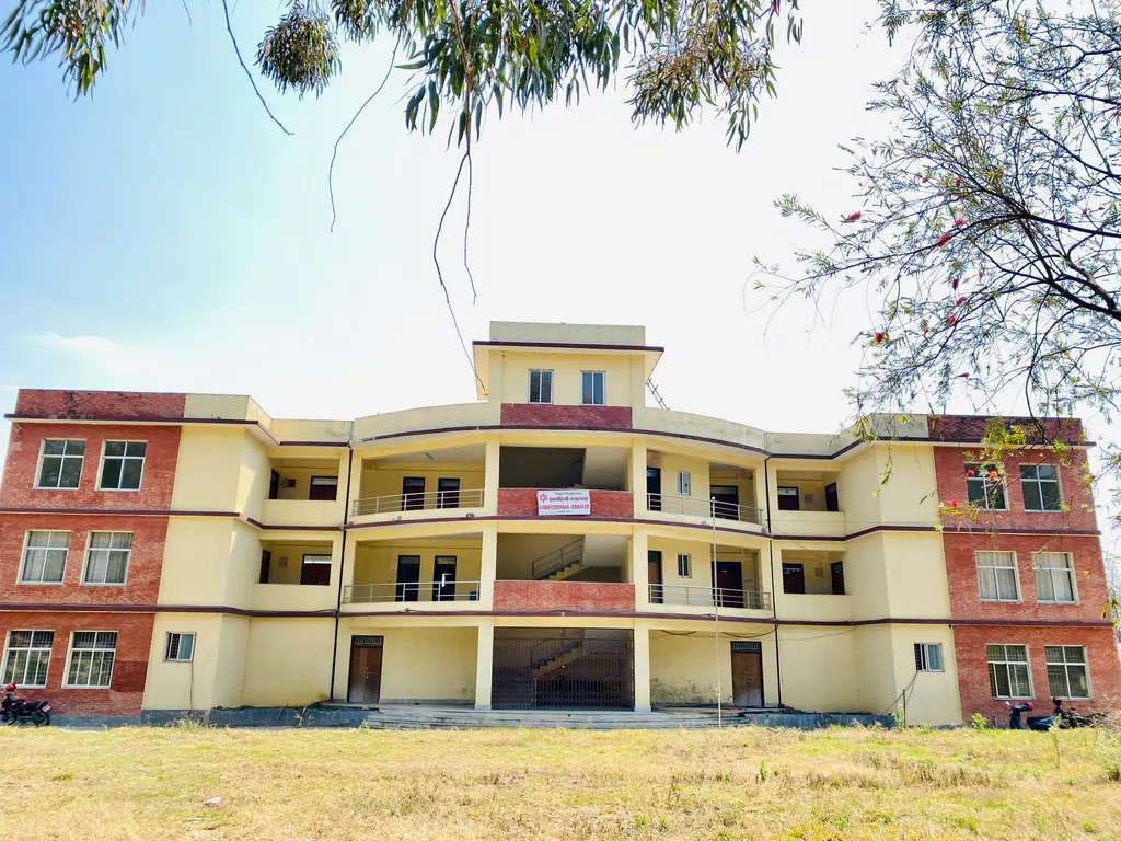 The three-storey campus block in cream and red brick, seen across open ground