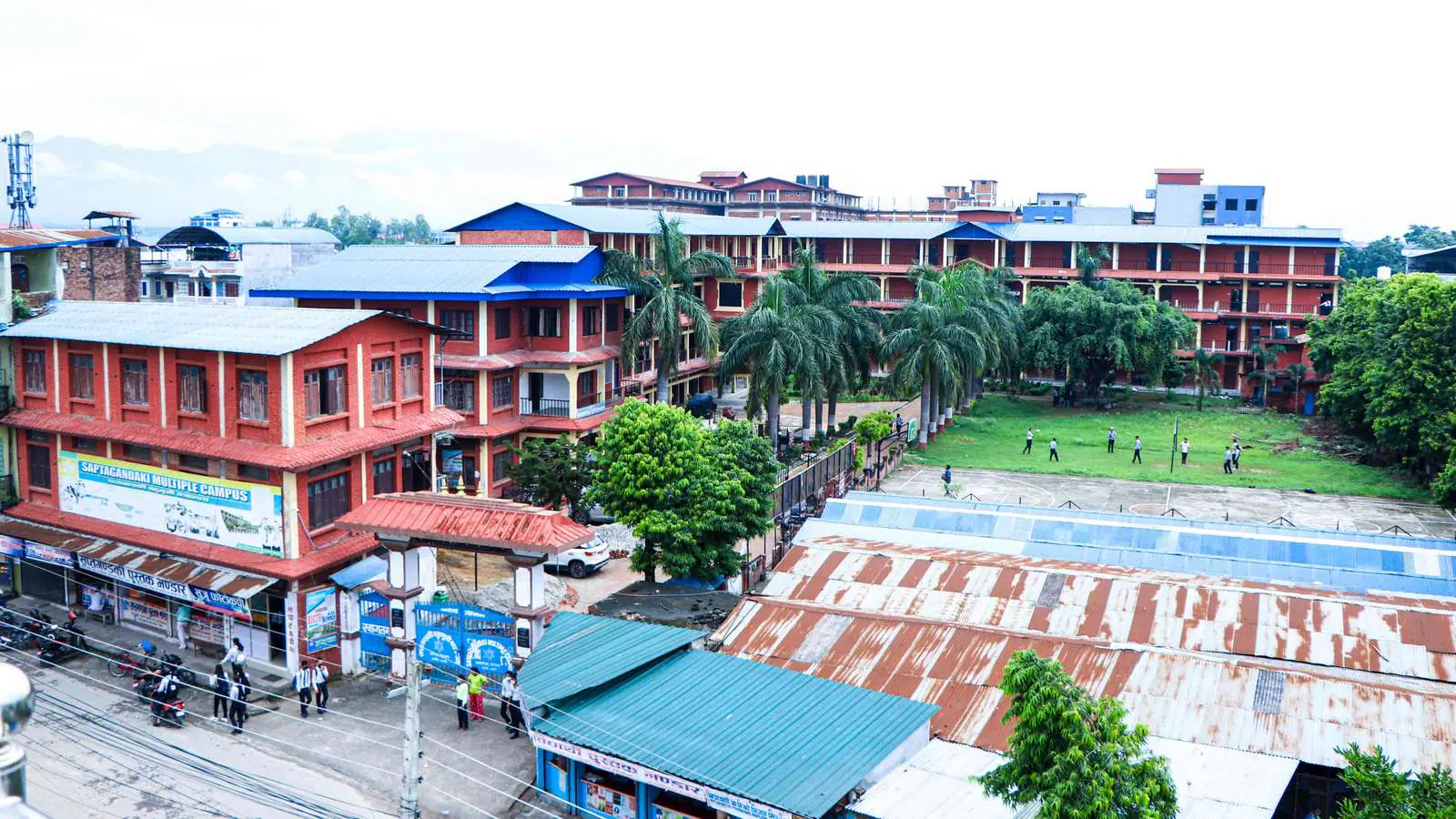 Aerial view of the red and blue campus blocks around a green playing field beside the highway