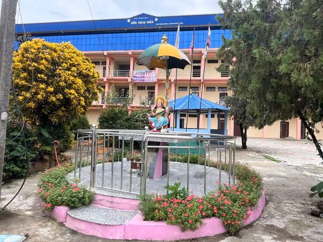 A flowering garden and shrine in front of the blue and cream college block