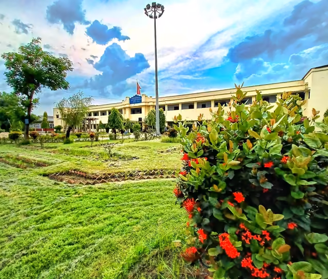 Flowering shrubs on the campus lawns, a long block and the flagpole behind them